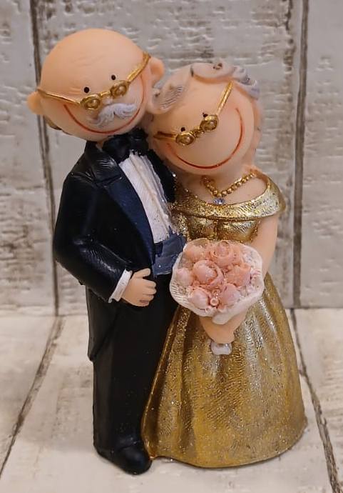 Brautpaar zur goldenen Hochzeit mit goldfarbenen Brillen, Braut im goldfarbenen Kleid mit rosa Blumenstrauß und Bräutigam im schwarzen Anzug, 10 cm