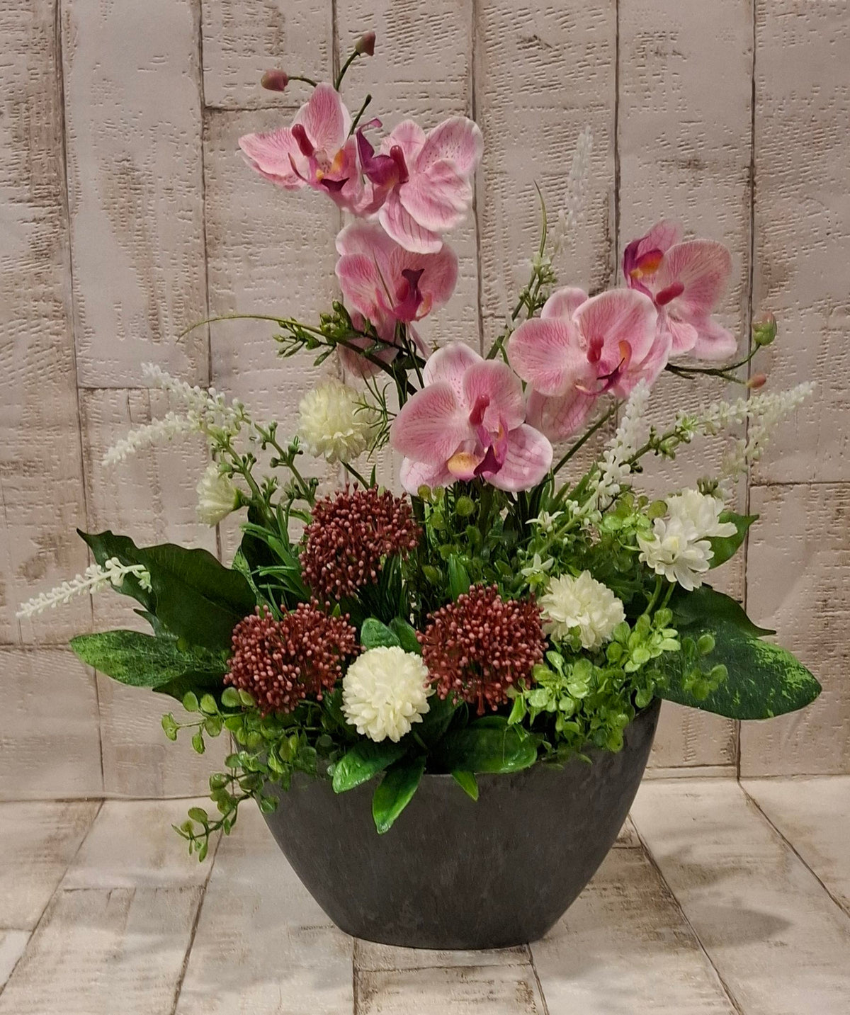 Orchideen-Gesteck von schräg oben mit rosa Blüten und weißen Akzenten