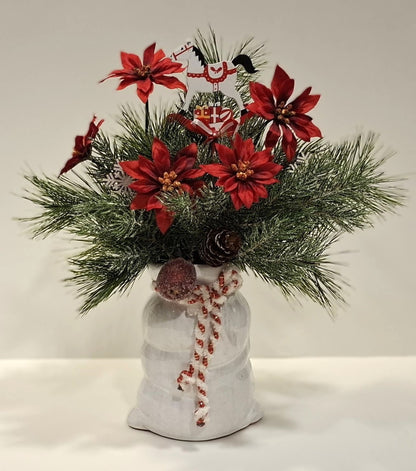 Weihnachtsgesteck im weißen Porzellansack mit roten Blüten und weiß-rotem Dekopferd – Gesamtansicht
