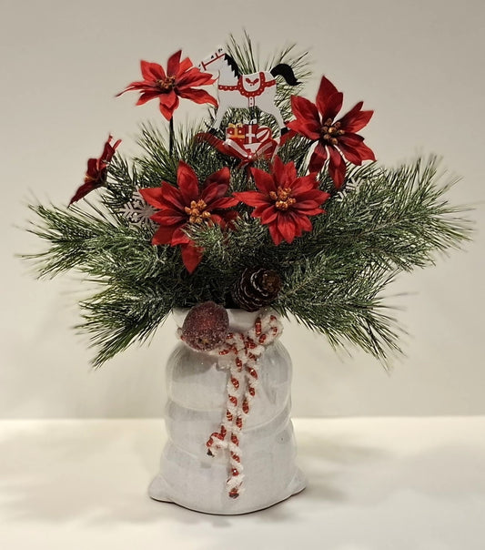 Weihnachtsgesteck im weißen Porzellansack mit roten Blüten und weiß-rotem Dekopferd – Gesamtansicht