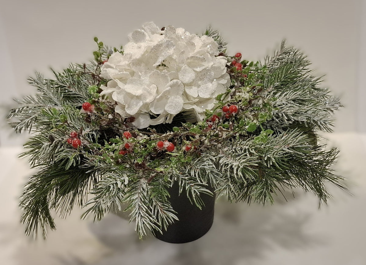 Großes Weihnachtsgesteck mit weißer Glitter-Hortensie, roten Beeren und winterlichen Zweigen im dunklen Keramikgefäß