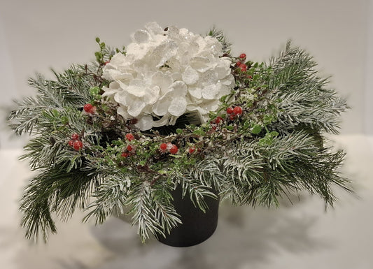 Großes Weihnachtsgesteck mit weißer Glitter-Hortensie, roten Beeren und winterlichen Zweigen im dunklen Keramikgefäß