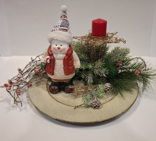 Weihnachtsgesteck auf goldfarbenem Teller mit Schneemann, roten Beeren und roter Kerze