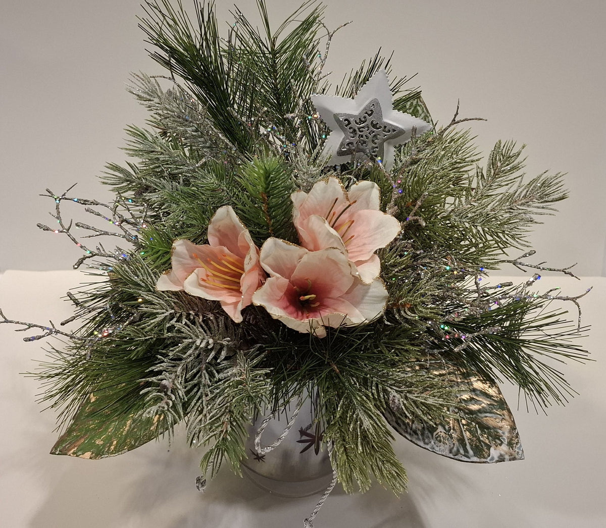 Handgefertigtes Weihnachtsgesteck im Glas mit Fuß, mit zarten Blüten, grünen Zweigen und Stern