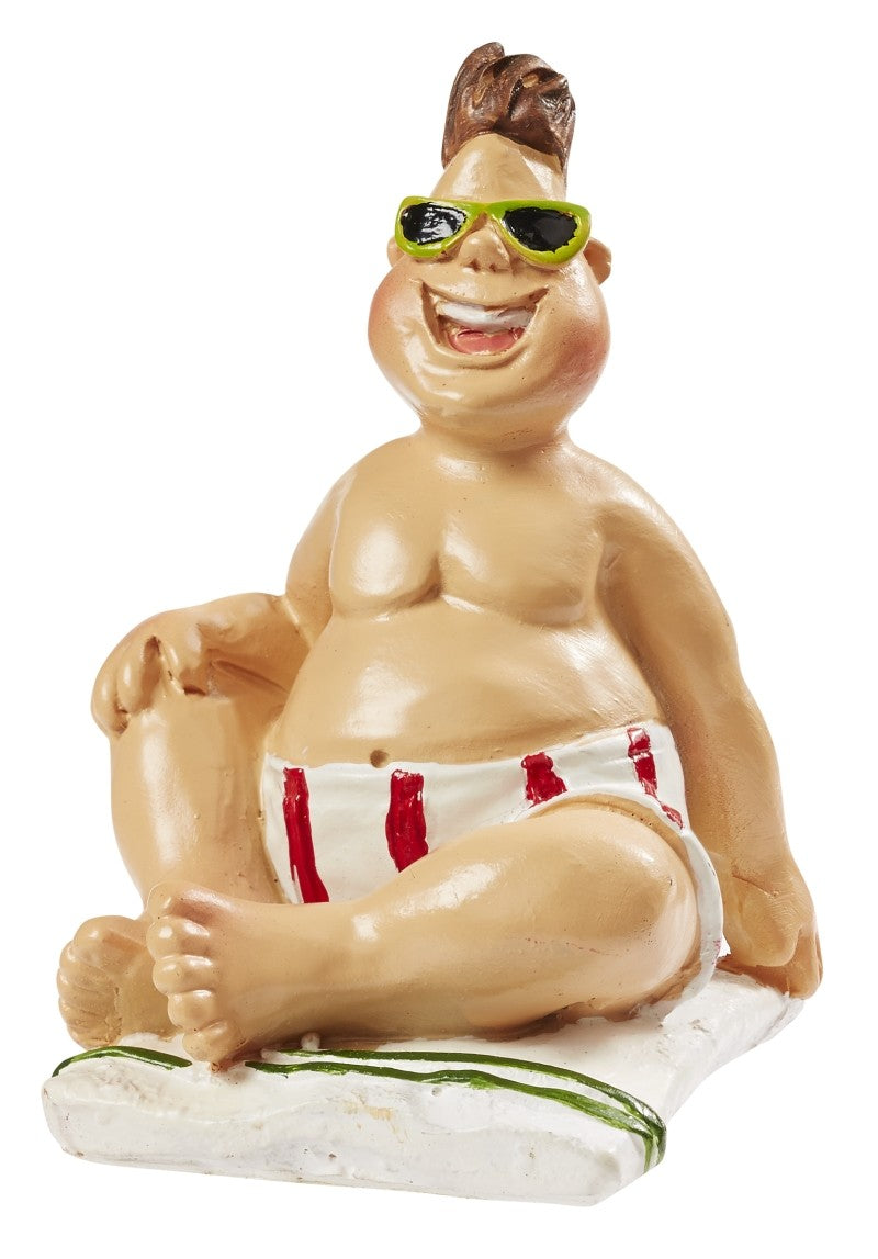 Sitzender Miniatur-Urlauber mit grüner Sonnenbrille und weiß-rot gestreifter Badehose auf einem Handtuch