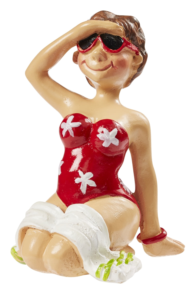Sitzende Miniatur-Urlauberin mit roter Sonnenbrille und rotem Badeanzug mit weißen Blumen